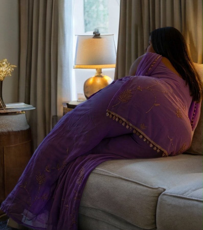 A woman in a purple embroidered dupatta sitting quietly in a warmly lit room